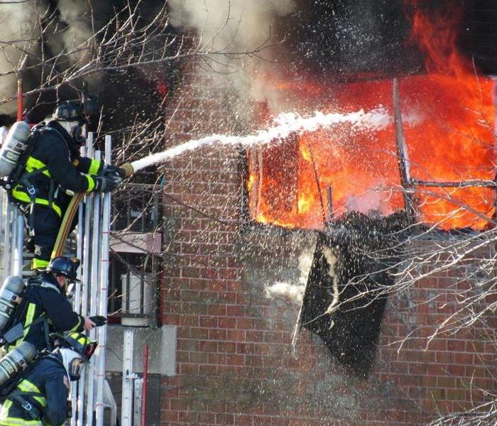 Fire fighters putting out a fire in a brick building